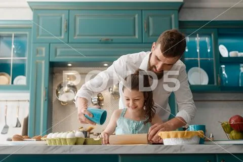 Daughter cooking with daddy in kitchen, preparing a sweet gift for mother Stock Photos