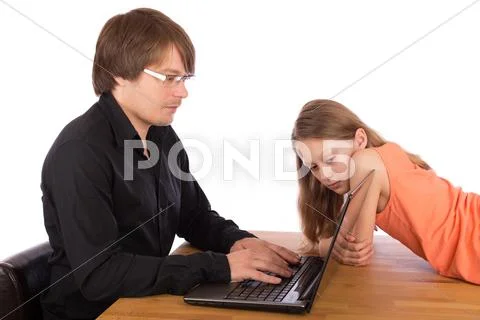 Daughter looks at her father's laptop Stock Photos
