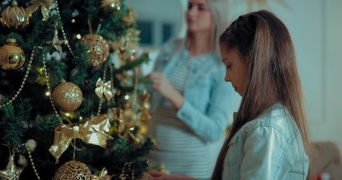 Daughter with mom decorate the Christmas tree. Girl hangs shirki and toys on the Stock Footage 101719853