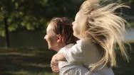 Daughter Riding Mothers Back In A City Park At Sunset. Slow Motion Stock Footage