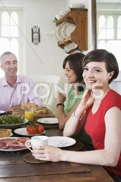 Daughter Sat At Dining Table With Her Father And Mother