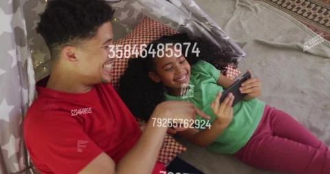 Daughter tapping smartphone in tent while father pointing animated data overlay Stock Footage 313294618