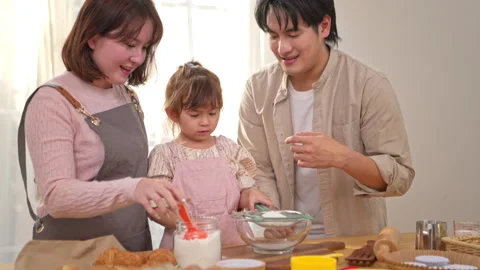 The daughter is using flour as an ingredient in a bowl Stock Footage 338427762