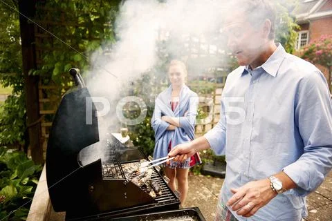 Daughter Watching Father Cook Sea Food On Barbecue