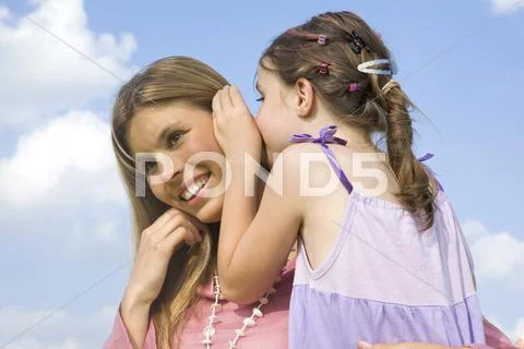 Daughter whispering in mother´s ear Stock Photos