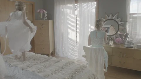 Daughters dancing on bed while mother applying lip balm on lips in bedroom Stock Footage 99998671