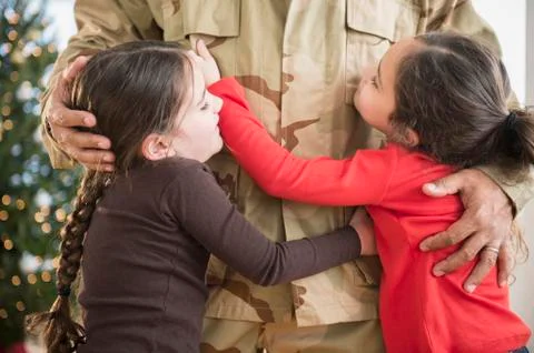 Daughters hugging soldier father Stock Photos