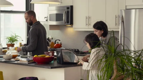 Daughters toasting a bread while father working in kitchen Stock Footage 63860931