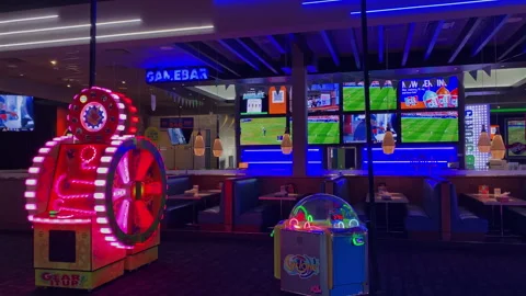 Dave and Buster's game bar and dining area with sports screens and arcadeDave-19 Stock Footage 339491024