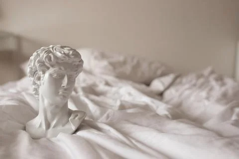 David's plaster head stands on a white bed. Stock Photos
