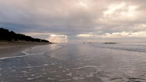 Dawn on a beach, rays of sun filtering through the clouds, soft waves wetti.. Stock Footage 272275858