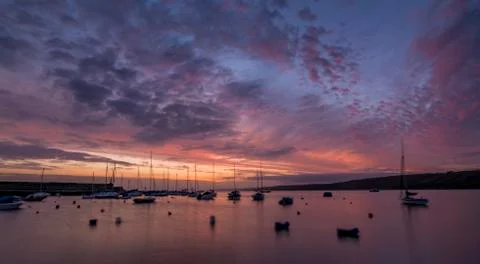 Dawn breaking over a harbour with small boats and yachts Stock Photos