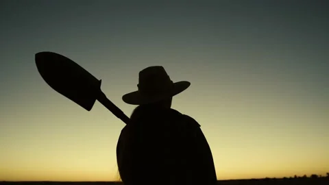 Dawn, farmer goes to work. Growing, food. Silhouette of farmer with shovel in Stock Footage 175393269