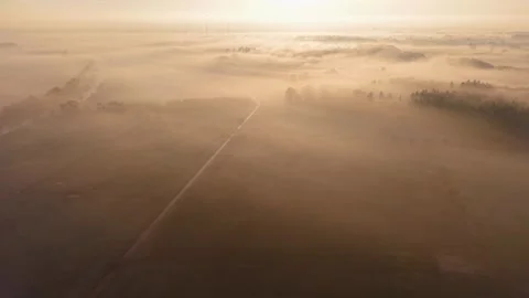 At dawn, fields and trees are shrouded in thick fog, a river flows through 库存影片 328011126