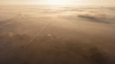 At dawn, fields and trees are shrouded in thick fog, a river flows through Stockbeeldmateriaal 328680235