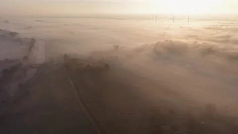 At dawn, fields and trees are shrouded in thick fog, a river flows through 스톡 동영상 329191267
