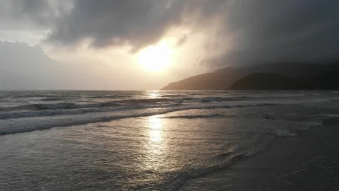 At dawn the flying camera flies beautifully over the beach overlooking the sea Stock Footage 100190442