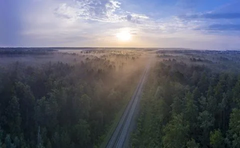 Dawn over the forest through which the railway line runs. Stock Photos