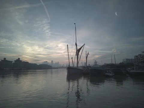 Dawn over River Thames (2). Sailing barge, docklands, moon. 16x9. Stock Photos