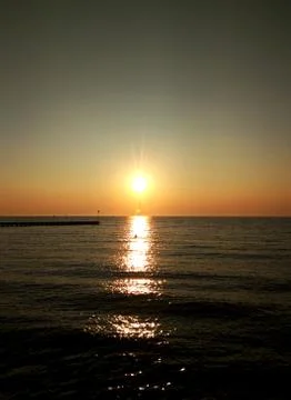 Dawn sky background with sun rays and reflected in the sea water Stock Photos