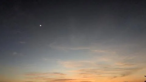 A dawn sky featuring a bright crescent moon and a vivid color gradient from.. Stock Photos