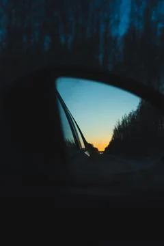 The dawn sky is reflected in the side mirror of the car Stock Photos