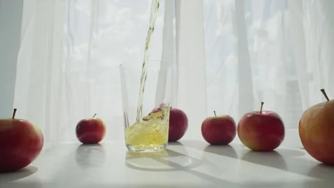 At dawn, soft rays illuminate the process of pouring fresh apple juice. Video stock 243561486