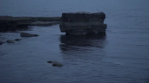 At dawn a tiny tide or wave hitting a boulder in the sea near Portland, 스톡 동영상 208839682