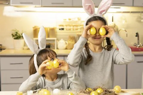On the day of bright Easter, children in bunny ears with painted eggs have fun Stock Photos