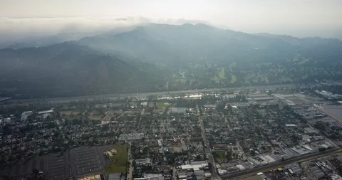 Day, High and Wide Over Freeway with Mountains, Sun, In The Clouds Stock Footage 129645896