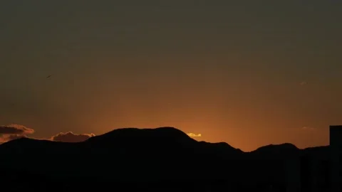 Day to night sunset orange sky silhouet mountains time lapse Stockbeeldmateriaal 151691992