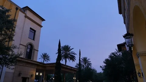 Day to Night Timelapse with Lanterns Turning on, City Hotel Building and Palms Stock Footage