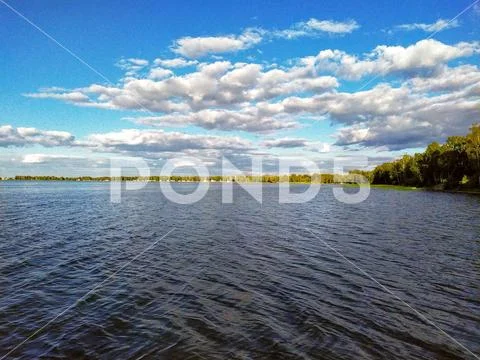 Day surface of the lake with beautiful cumulus clouds. Stock Photos