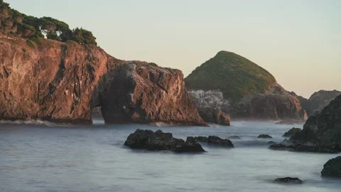 Day time seascape of smooth ocean waves around rocks and a sea cave - timelapse Stock Footage 219760786