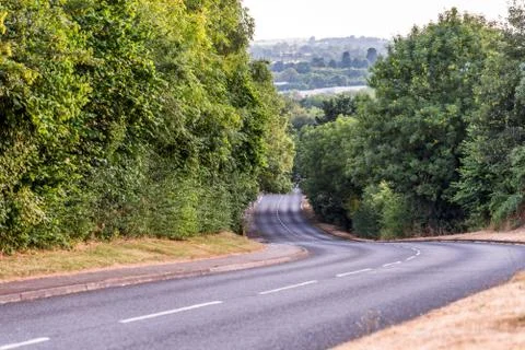 Day view empty British curved road between trees in Northampton England Photos