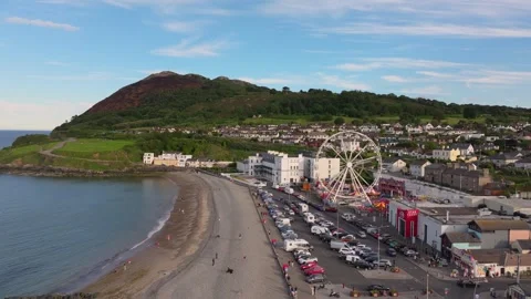 Daylight Carnival Rides and Beachfront Parking beside Irish Coastal Headland Stock Footage 338068226