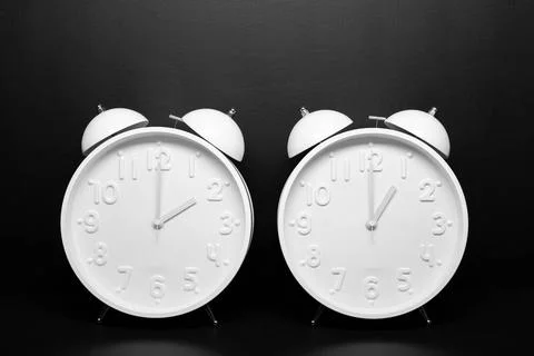 Daylight saving time concept. Two White Retro clock isolated on black back... Foto stock