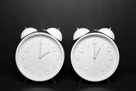 Daylight saving time concept. Two White Retro clock isolated on black Stock Photos