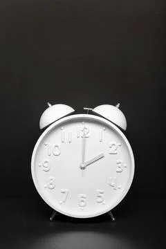 Daylight saving time concept. White Retro clock isolated on black background. Stock Photos