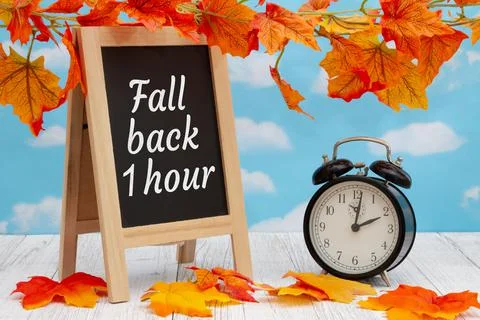 Daylight Saving Time fall back sign with alarm clock on weathered wood with f Stock Photos