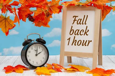 Daylight Saving Time fall back sign with alarm clock on weathered wood with f Stock Photos