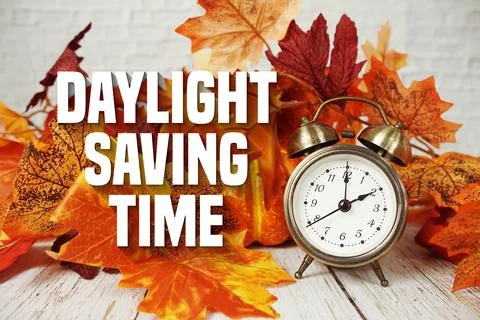 Daylight Saving Time text with alarm clock and maple leaf decoration on woo.. Fotos Stock