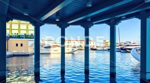 Daylight view from dark awning to parked luxury yachts Stock Photos