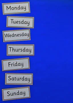 Days of the week flatlay on blue background. Stock Photos