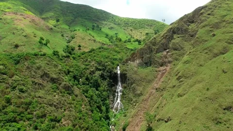 Daytime Aerial Drone View Of Tall Waterfall Cascading Down Green Mountains Near Stock Footage 345241333