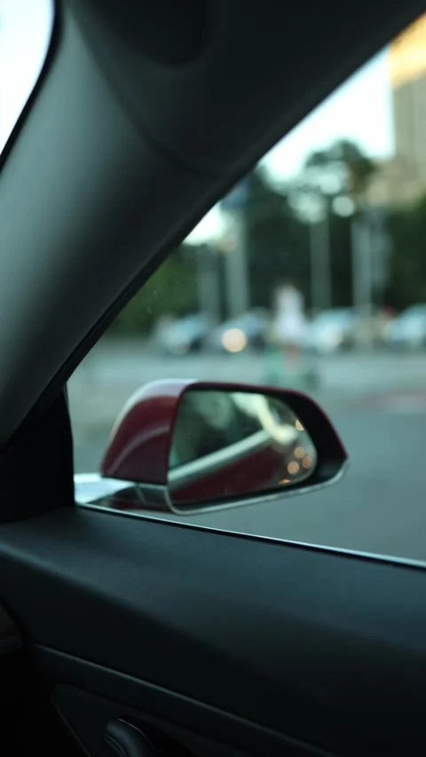 Daytime city streets reflected through a moving cars rearview mirror Stock Footage 346545820