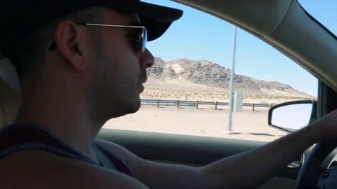 Daytime Close-up of Man driving by mountains. Stock Footage 81596327