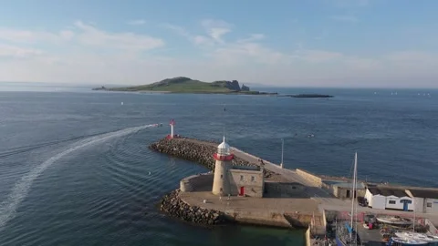 Daytime Drone Pullback from Stone Breakwater and Boats toward Ireland’s Eye Stock Footage 339409368