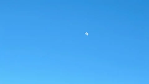 Daytime moon moving across clear blue sky timelapse. Stock Footage 328336744