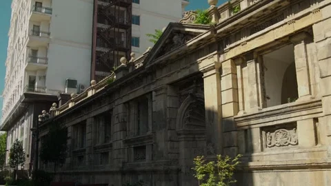 Daytime Pan of Old Ornate Stone Structure with Modern Building Background Stock Footage 338243617